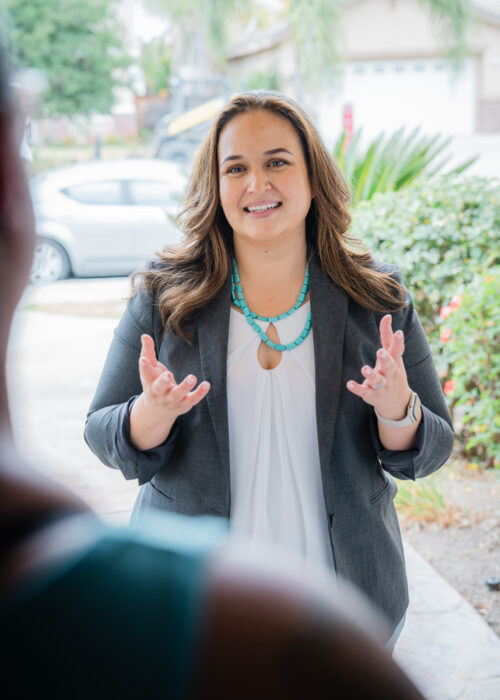 Lupe Gomez speaking with a Perris resident at a doorway.